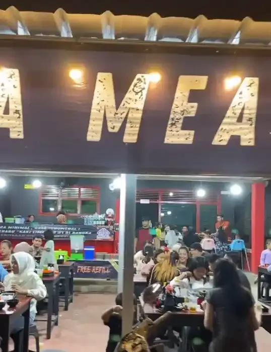 Huruf besar MEAT di dinding kedai pada malam hari